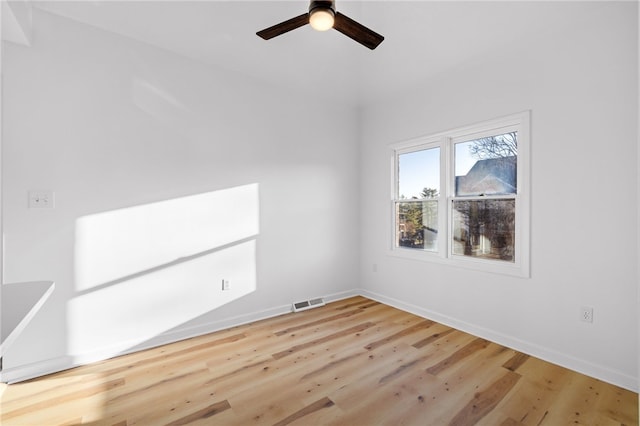 spare room with a ceiling fan, visible vents, baseboards, and wood finished floors