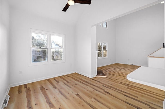 empty room featuring high vaulted ceiling, wood finished floors, visible vents, baseboards, and a ceiling fan