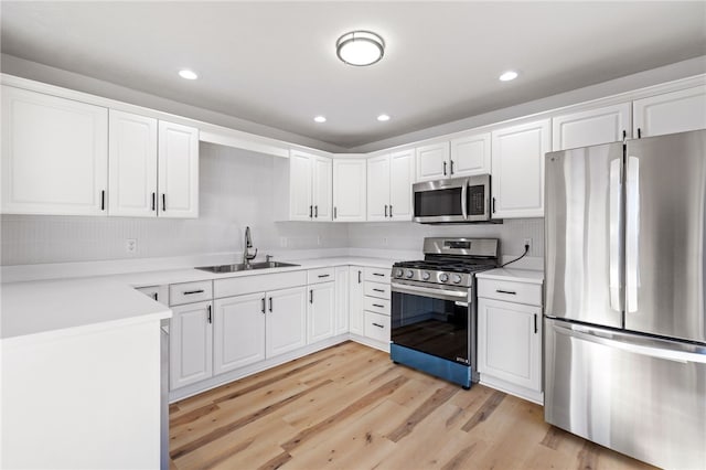 kitchen with light wood-style flooring, stainless steel appliances, white cabinetry, a sink, and recessed lighting