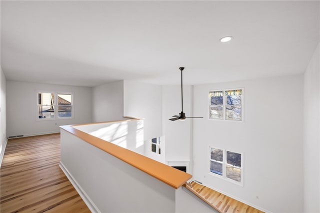 hall featuring light wood finished floors, recessed lighting, visible vents, an upstairs landing, and baseboards