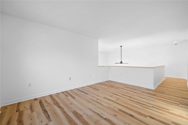 empty room featuring light wood-style floors, ceiling fan, and baseboards