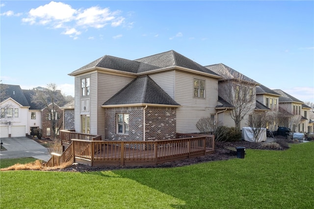 back of house with a shingled roof, a lawn, a wooden deck, and brick siding