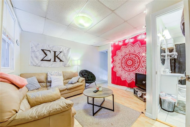 living area with wood finished floors, a paneled ceiling, and baseboards