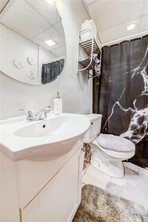 bathroom featuring toilet, vanity, a paneled ceiling, and a shower with curtain