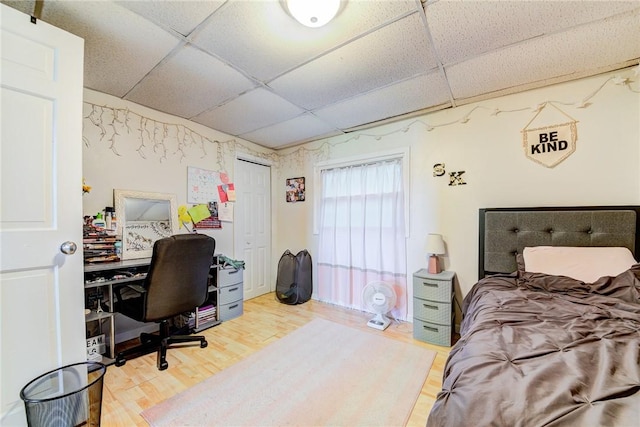 bedroom with a paneled ceiling and wood finished floors