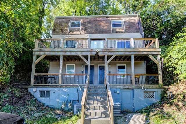 view of front of property featuring covered porch, stairway, and mansard roof