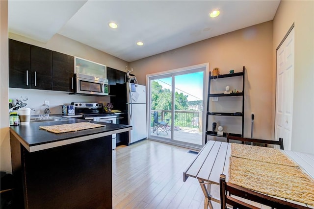 kitchen featuring dark countertops, light wood-style flooring, appliances with stainless steel finishes, dark cabinets, and recessed lighting