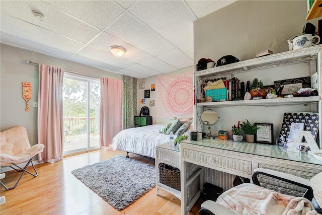 bedroom featuring wood finished floors, a paneled ceiling, and access to exterior