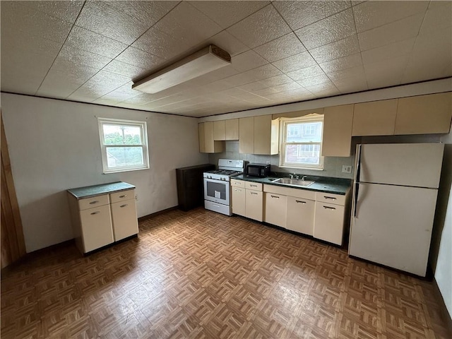 705 E 18th Ave, Munhall, PA 15120 - kitchen featuring white appliances, dark countertops, a sink, and cream cabinets