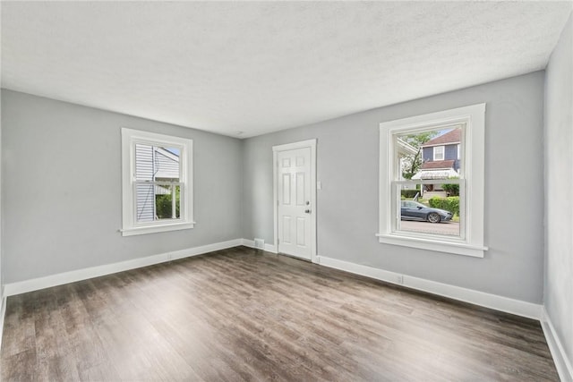 spare room featuring dark wood-style floors, a textured ceiling, and baseboards