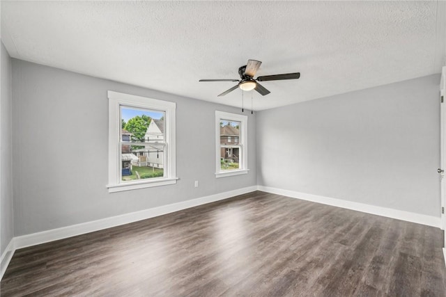 spare room featuring baseboards, a textured ceiling, ceiling fan, and dark wood-style flooring