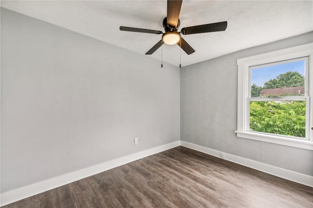 spare room featuring baseboards, ceiling fan, and dark wood-style flooring