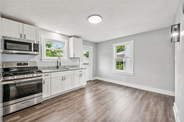 kitchen featuring a sink, white cabinetry, appliances with stainless steel finishes, baseboards, and dark wood-style flooring
