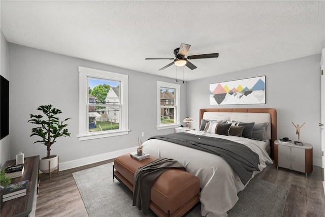 bedroom featuring ceiling fan, wood finished floors, baseboards, and a textured ceiling