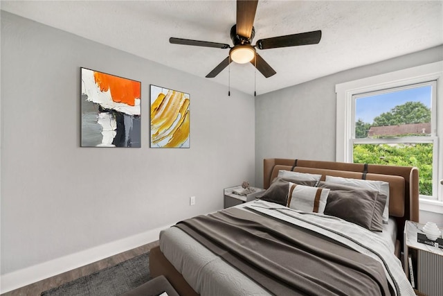 bedroom with ceiling fan, baseboards, multiple windows, and wood finished floors