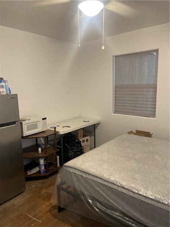 bedroom with a ceiling fan, wood finished floors, and freestanding refrigerator