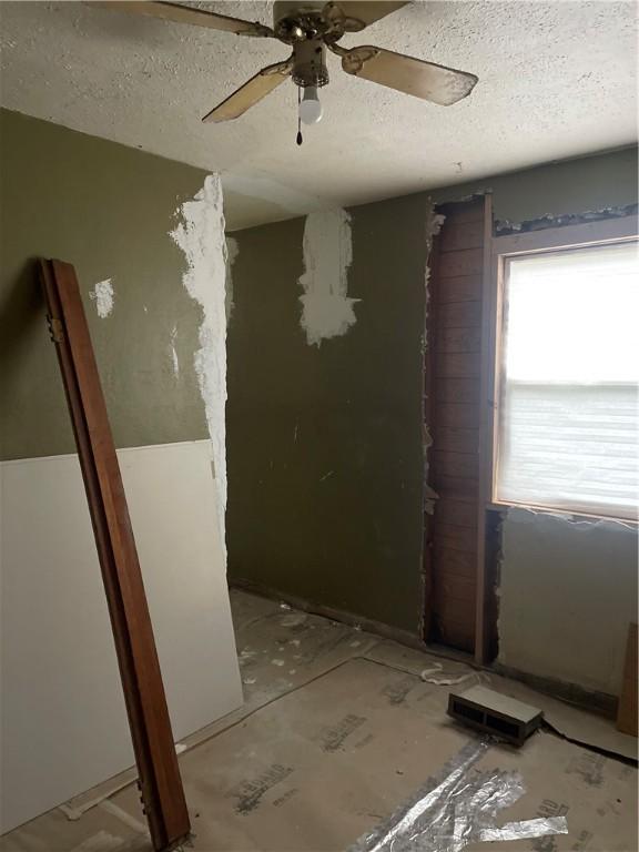 unfurnished room with a ceiling fan and a textured ceiling