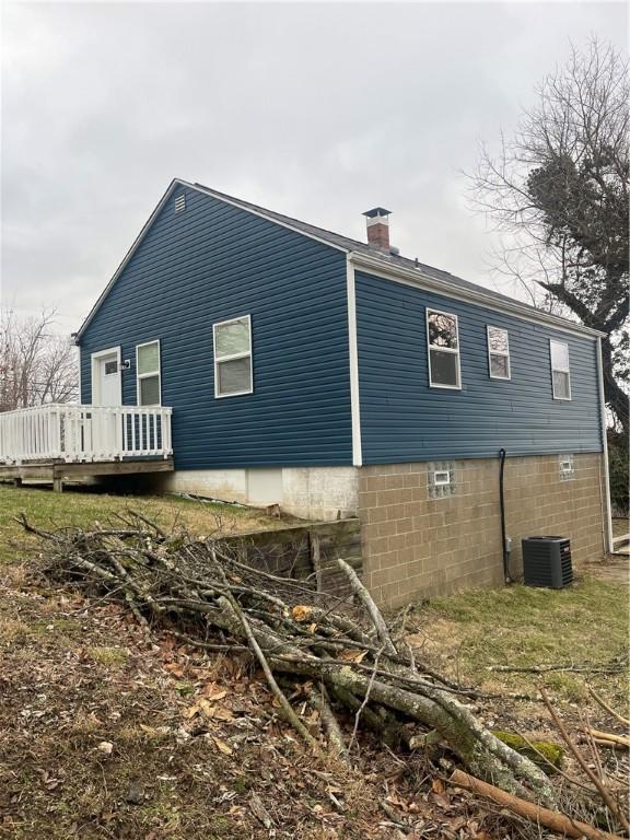 view of home's exterior with a chimney, central AC, and a wooden deck