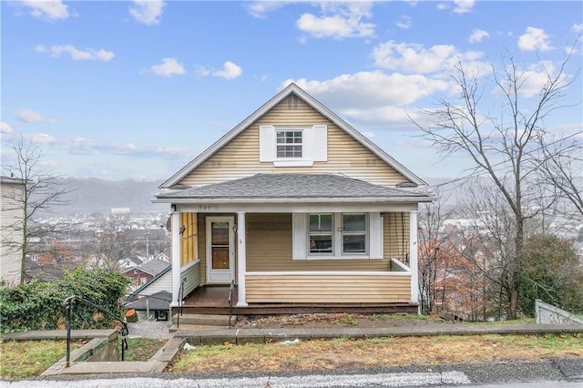 bungalow-style home featuring a porch and roof with shingles