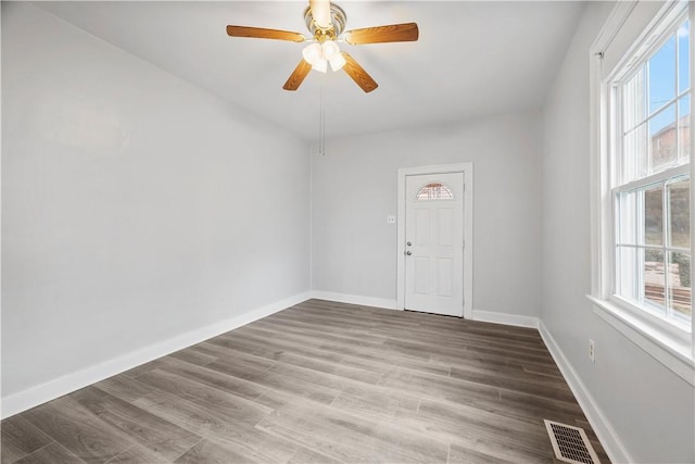 spare room featuring a ceiling fan, wood finished floors, visible vents, and baseboards