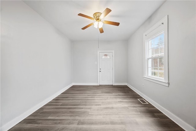 empty room with a ceiling fan, visible vents, baseboards, and wood finished floors