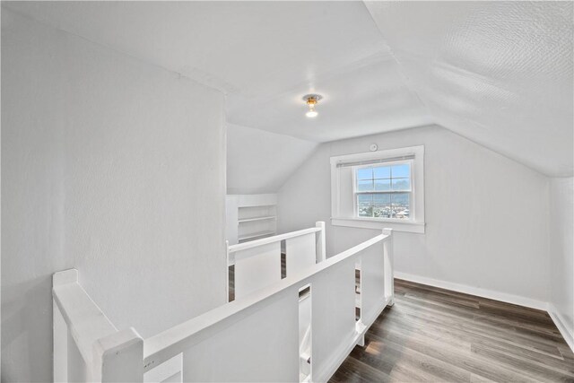 additional living space with baseboards, vaulted ceiling, and wood finished floors