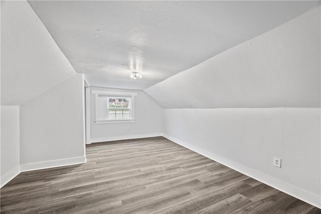 additional living space featuring vaulted ceiling, wood finished floors, and baseboards