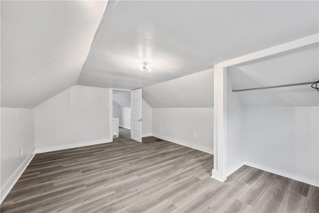 additional living space featuring baseboards, vaulted ceiling, and wood finished floors