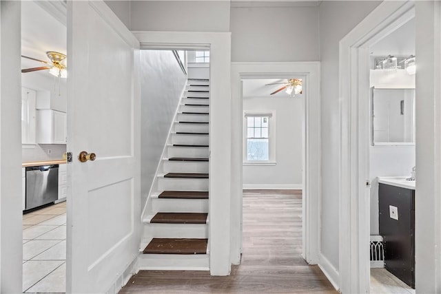 stairway featuring baseboards, a ceiling fan, and wood finished floors