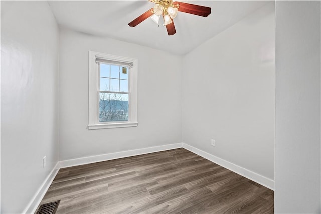 spare room featuring visible vents, baseboards, ceiling fan, and dark wood-style flooring