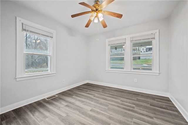 spare room with a ceiling fan, baseboards, visible vents, and wood finished floors