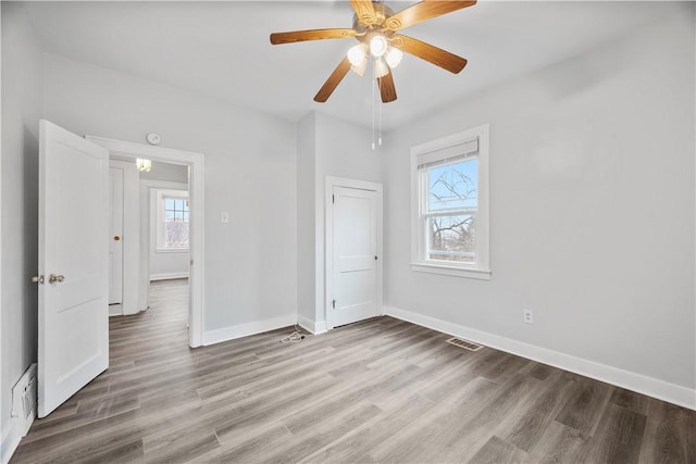 unfurnished bedroom with visible vents, a ceiling fan, light wood-style flooring, and baseboards