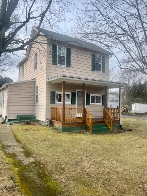 traditional-style house featuring covered porch and a front yard