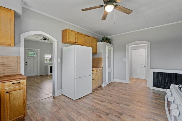 kitchen featuring arched walkways, decorative backsplash, ornamental molding, light wood-type flooring, and white appliances