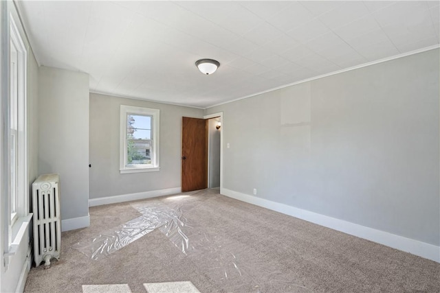 carpeted spare room with ornamental molding, radiator, and baseboards