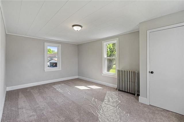 spare room featuring carpet, radiator heating unit, baseboards, and crown molding