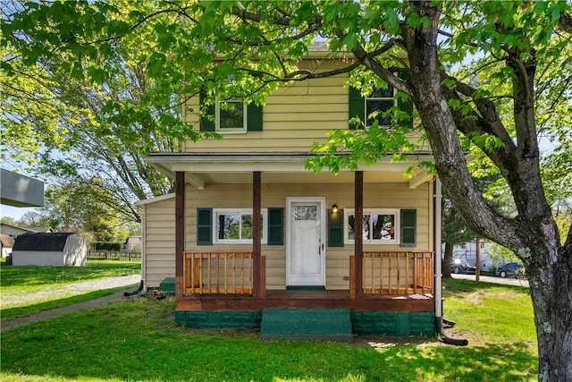 view of front of home featuring an outbuilding, a porch, a shed, and a front yard