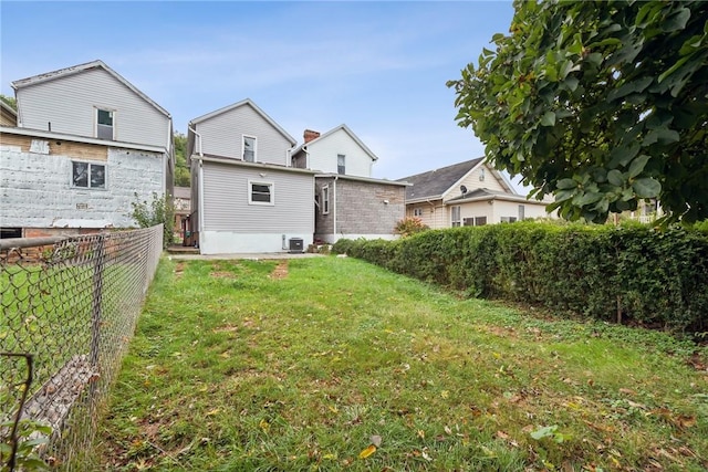 back of property featuring a yard, central AC, and fence