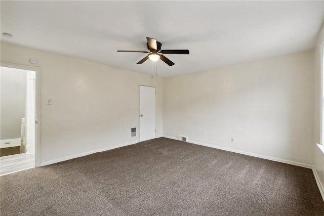 spare room featuring dark colored carpet, visible vents, and baseboards