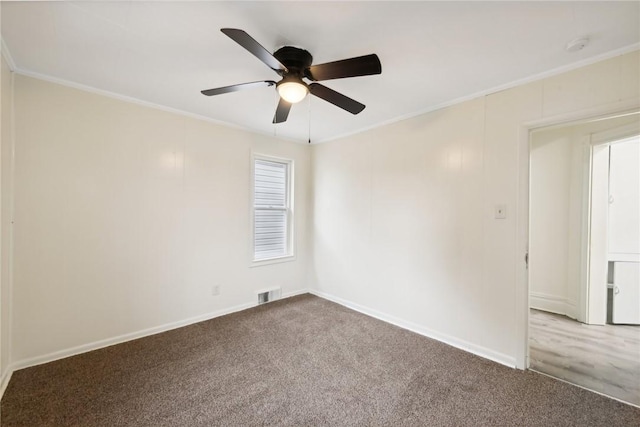 carpeted spare room with visible vents, a ceiling fan, crown molding, and baseboards