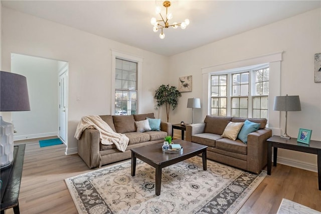 living room featuring an inviting chandelier, baseboards, and light wood finished floors