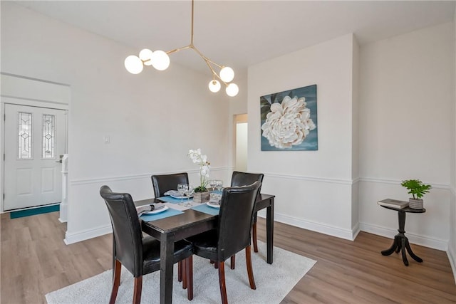 dining space with baseboards, a chandelier, and wood finished floors