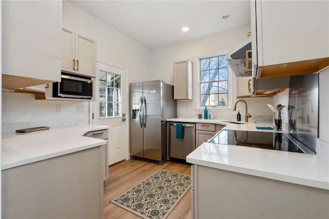 kitchen with recessed lighting, light countertops, appliances with stainless steel finishes, a sink, and light wood-type flooring