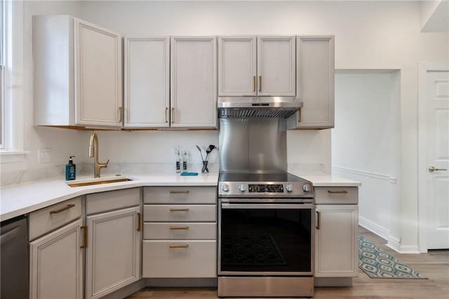 kitchen featuring under cabinet range hood, appliances with stainless steel finishes, gray cabinets, and a sink