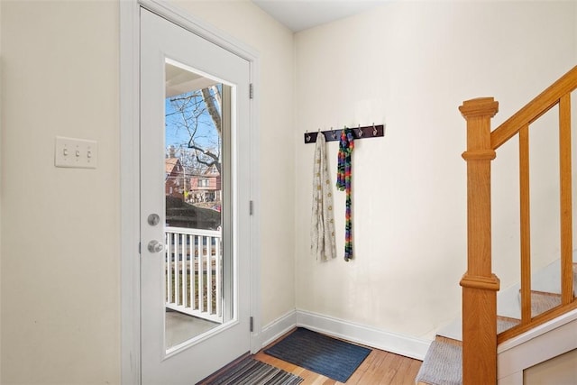 doorway with stairway, wood finished floors, and baseboards