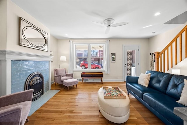 living area featuring light wood-style floors, a fireplace, stairway, and baseboards