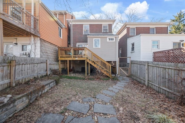 rear view of property featuring a fenced backyard, stairway, a gate, a deck, and brick siding