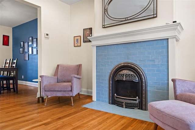 sitting room with light wood-style floors, baseboards, and a tiled fireplace