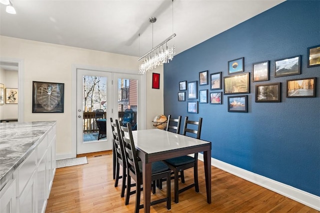 dining space with a notable chandelier, light wood finished floors, and baseboards