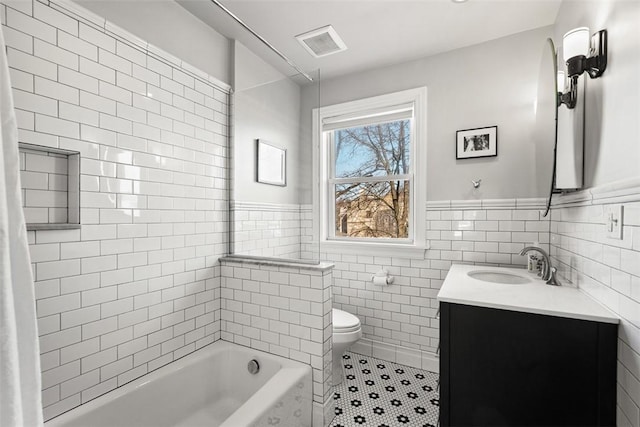 full bath with visible vents, toilet, tile patterned floors, a washtub, and tile walls